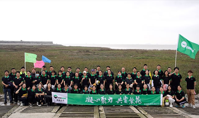 Team of employees holding a banner outdoors at Somewang Packaging company.