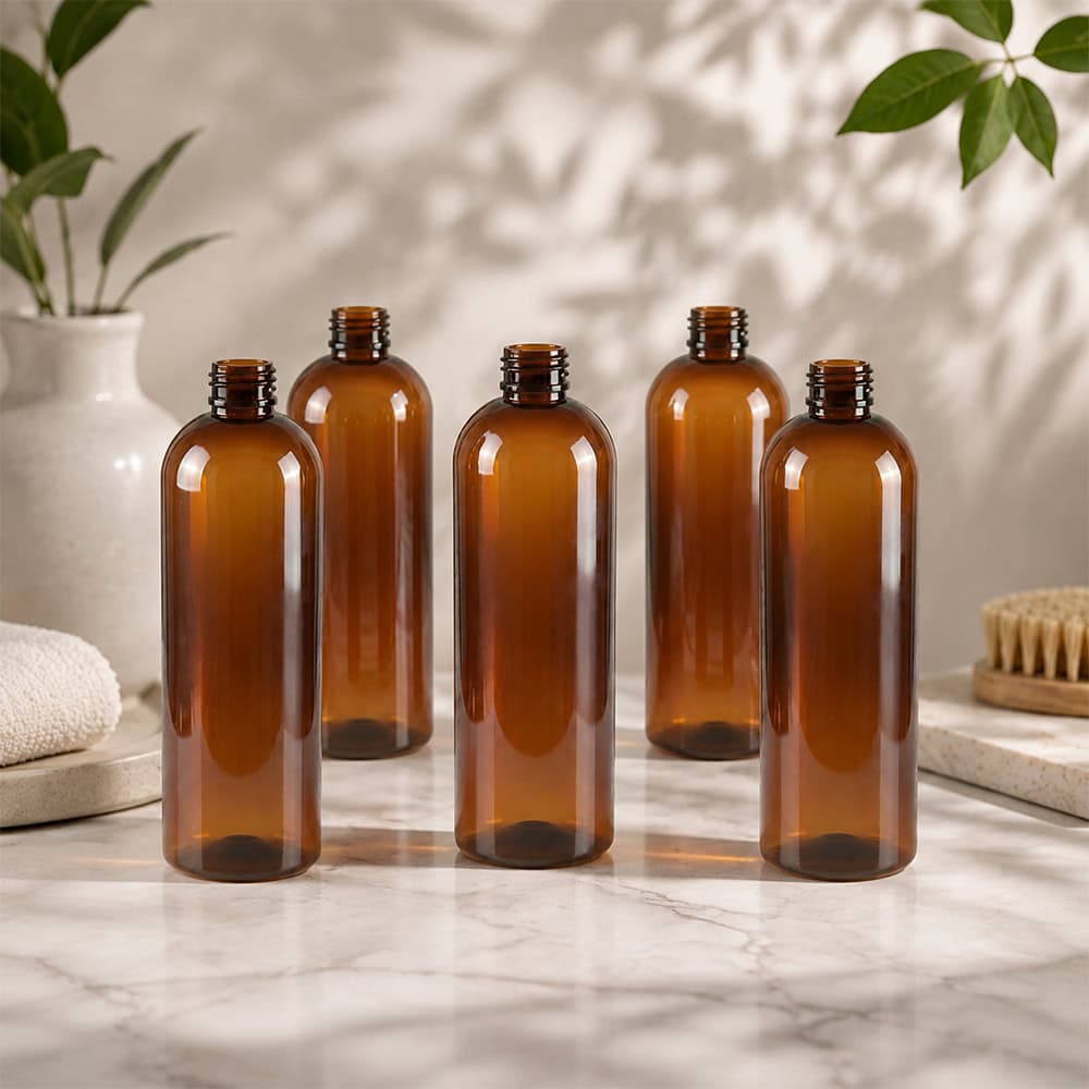 Set of five amber PET bottles on marble surface for packaging.