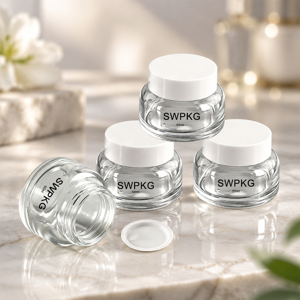 Set of three clear glass jars with white lids for packaging cosmetics or creams.